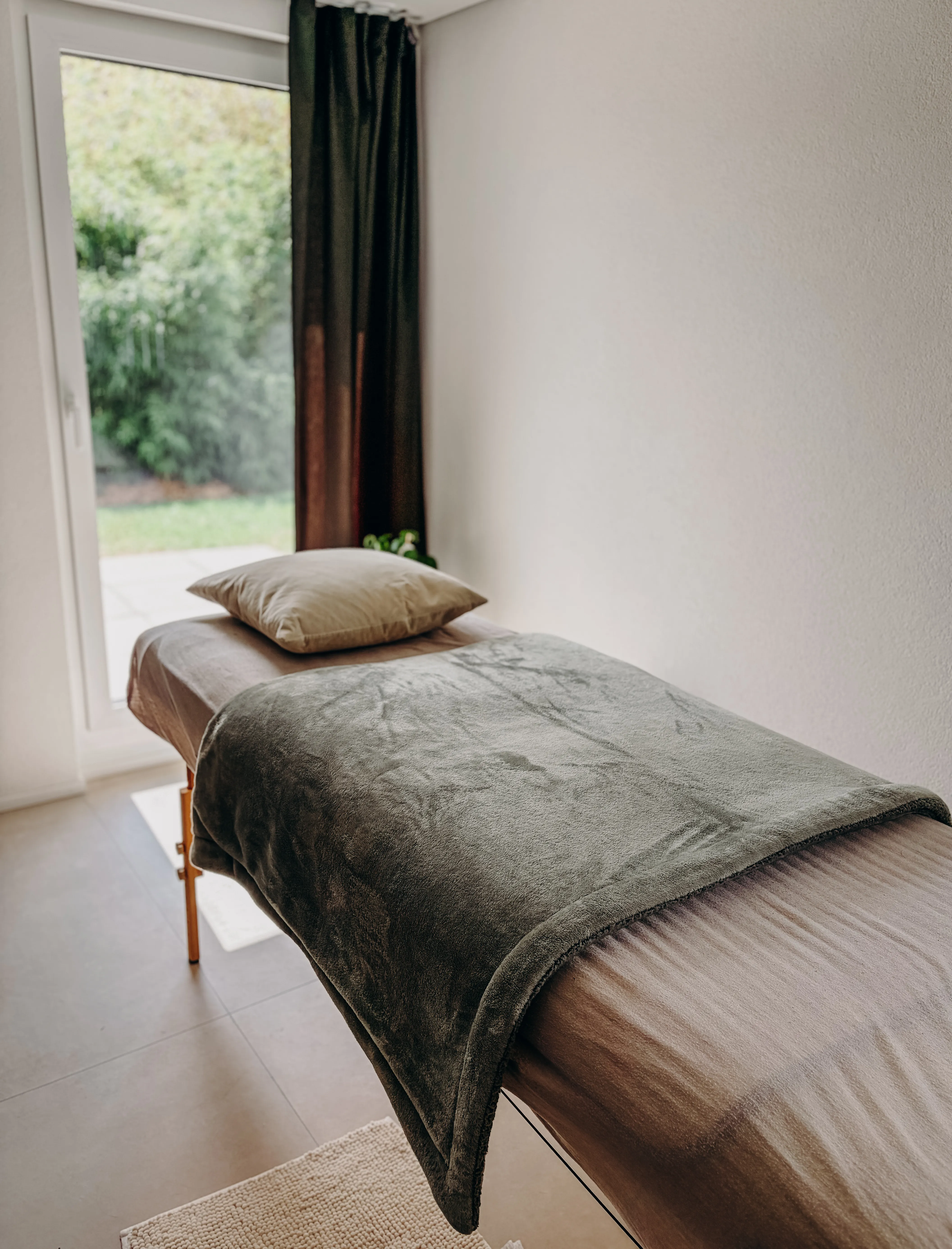 Une table de massage avec un couverture et un coussin dessus. Ambiance cosy.