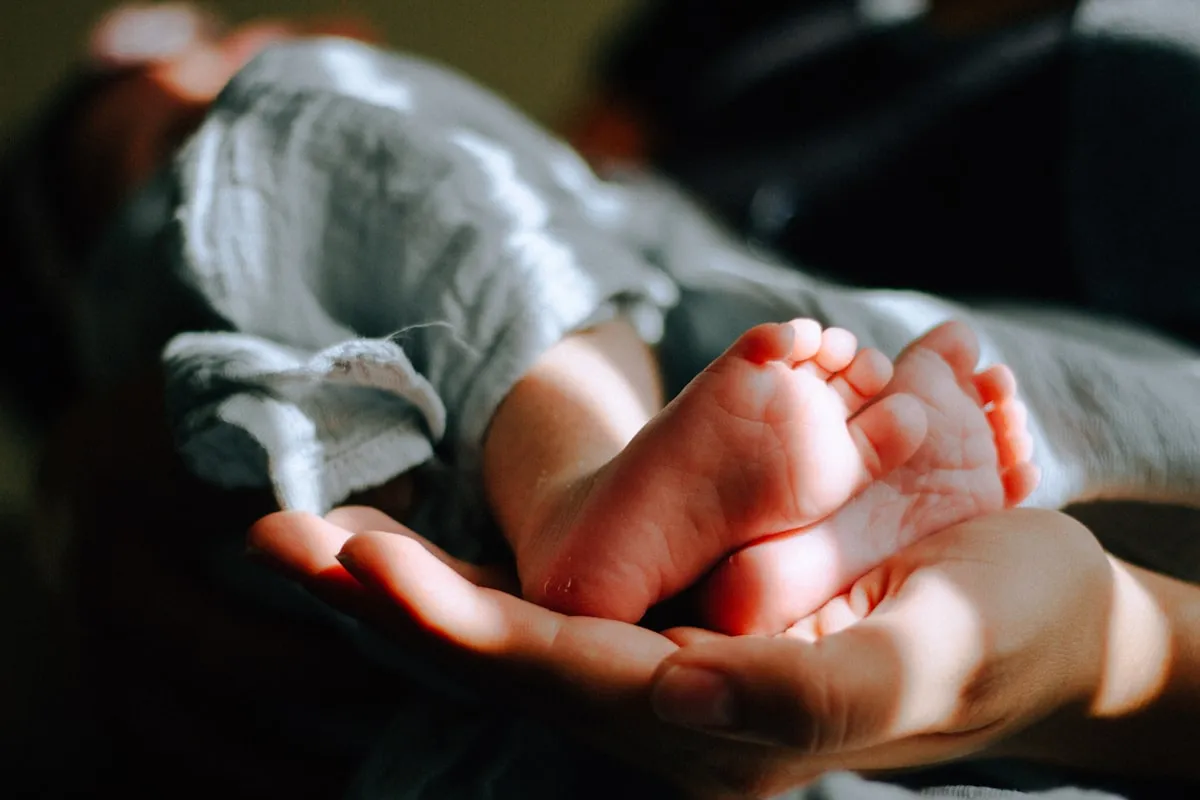 Les mains d’un adulte tiennent délicatement les pieds d’un bébé
